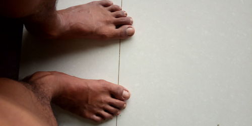 Cropped hand of person holding book against wall