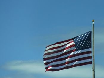 Low angle view of flag against blue sky