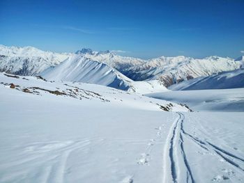 Scenic view of snow covered mountains against blue sky