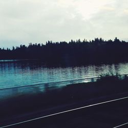 Calm lake with silhouette trees in background