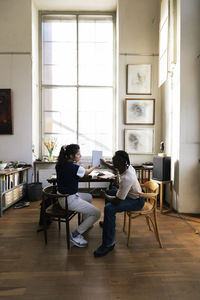 Side view of woman sitting on floor at home