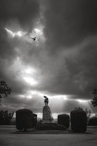 Statue in field against cloudy sky