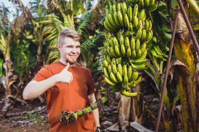 Portrait of young woman standing against plants