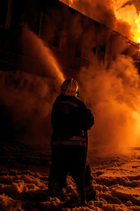 Firefighter spraying water on burning fire at night