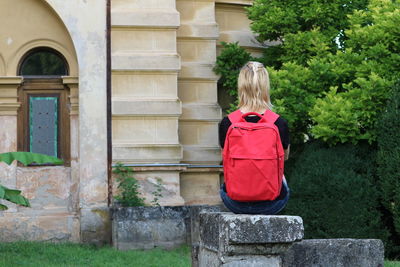 Rear view of woman sitting on rock by castle