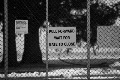 Close-up of information sign on chainlink fence