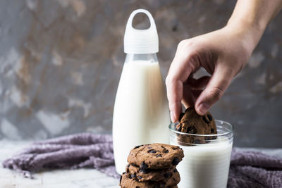 Cropped hand of man dipping cookie into milk