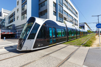 Train on railroad tracks by buildings in city against sky