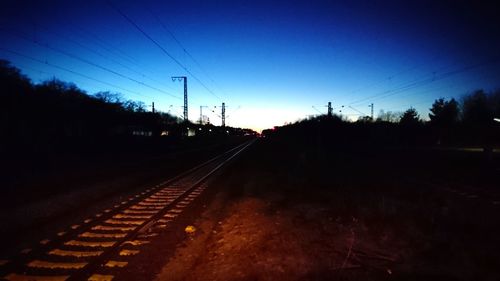 Railroad tracks against clear sky at sunset