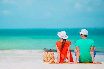 Rear view of people at beach against sky