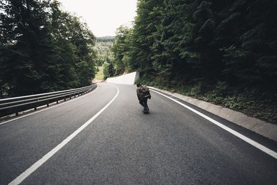 Man on road amidst trees