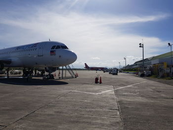 Airplane on airport runway against sky