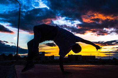 Silhouette man with umbrella against sky during sunset