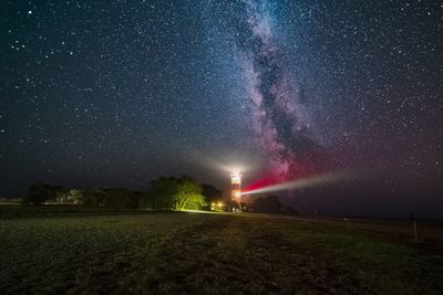 Scenic view of illuminated field against sky at night