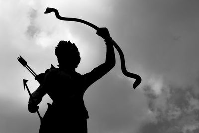 Low angle view of silhouette statue against cloudy sky