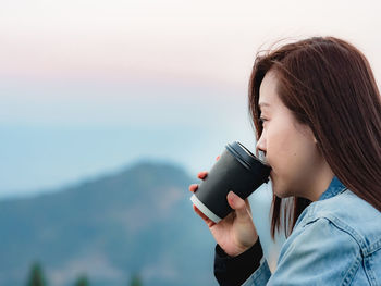 Midsection of woman holding coffee cup at mountain view of coffeebar 