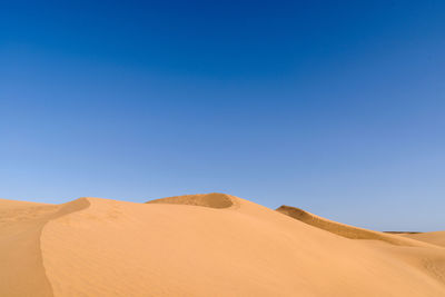 Scenic view of desert against clear blue sky