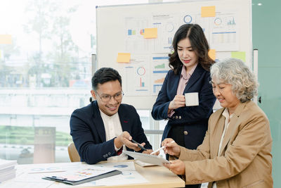 Group of business people sitting around the office desk and discussing the project together.