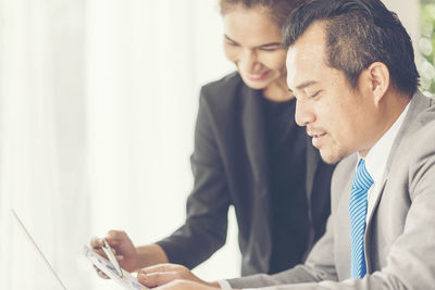 Colleagues discussing over laptop while sitting in office