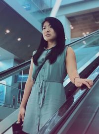 Young woman standing on escalator