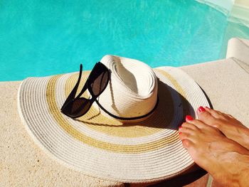 Low section of woman by hat and sunglass at poolside