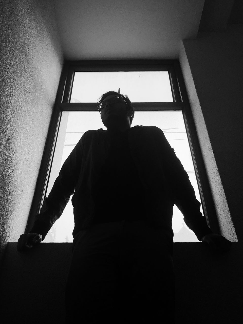 REAR VIEW OF WOMAN STANDING AGAINST WINDOW