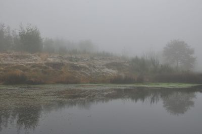 Scenic view of lake against sky during foggy weather