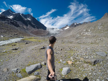 Side view of man looking away while taking selfie against sky