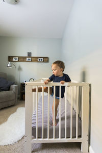 Baby boy standing in crib at home