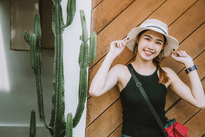 Portrait of smiling young woman standing against wall