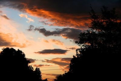 Low angle view of silhouette trees against dramatic sky