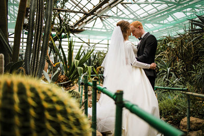 Rear view of couple standing in greenhouse