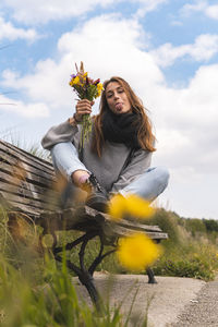 Woman with arms outstretched against sky and plants