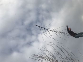 Low angle view of hand holding plant against sky