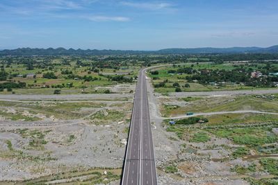 High angle view of road amidst field against sky