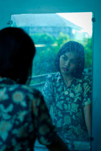 Rear view of woman looking through window