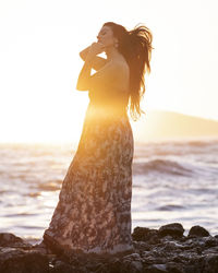 Woman standing at beach against sky