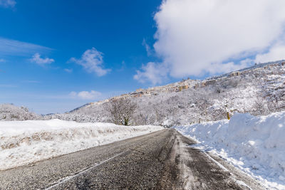 Road amidst snowcapped mountains against sky