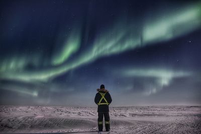 Full length of man standing on snow covered landscape at night