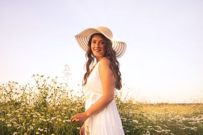 Portrait of smiling young woman standing by plants against sky