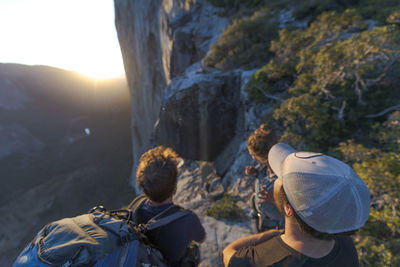 Three hikers looking at the nose el capitan from the top at sunset