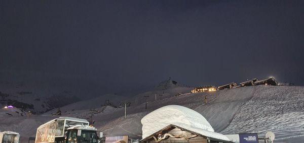 Snow covered buildings against sky at night