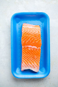 Fresh raw salmon in plastic container, close up view.