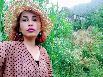 Portrait of beautiful young woman standing against plants