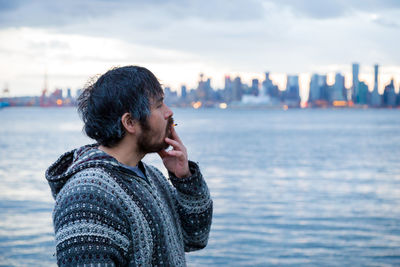 Man standing by sea against sky in city