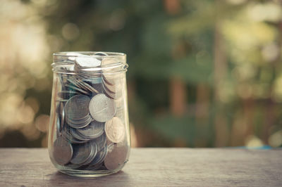 Close-up of coins in jar on wooden table