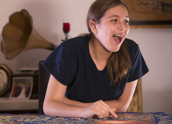 Happy teenage girl playing puzzle at home