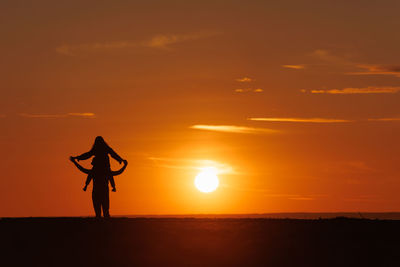Silhouette woman standing on beach against sky during sunset