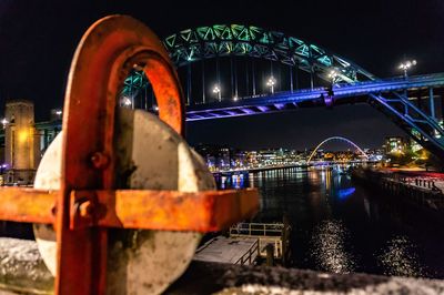 Low angle view of illuminated bridge over river in city at night