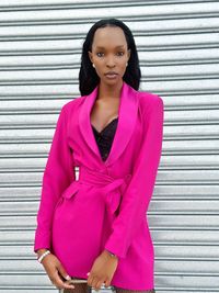 Portrait of young woman standing against wall